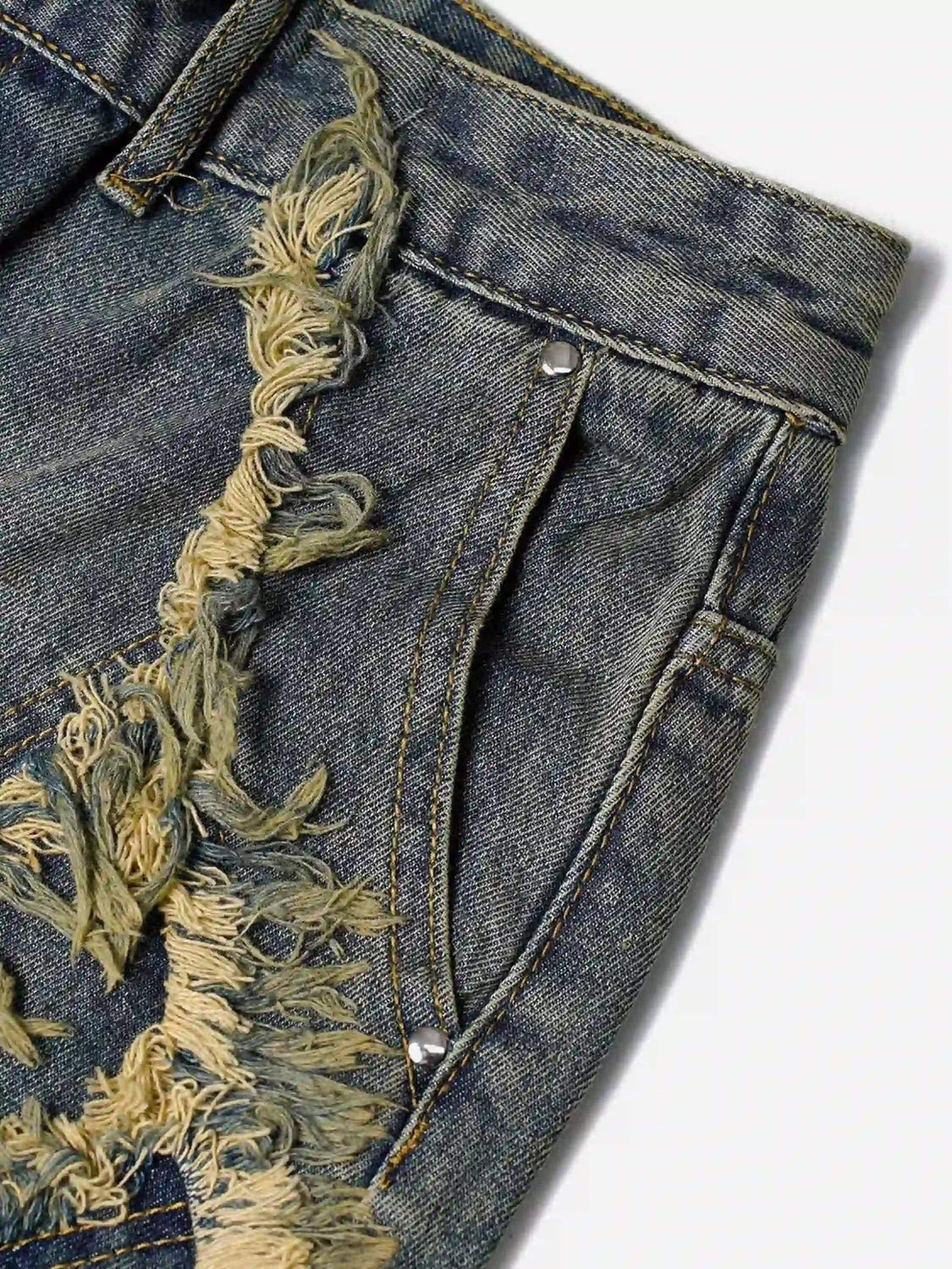 A tight crop highlighting TALISHKO denim jorts with intricate whisker patchwork details.