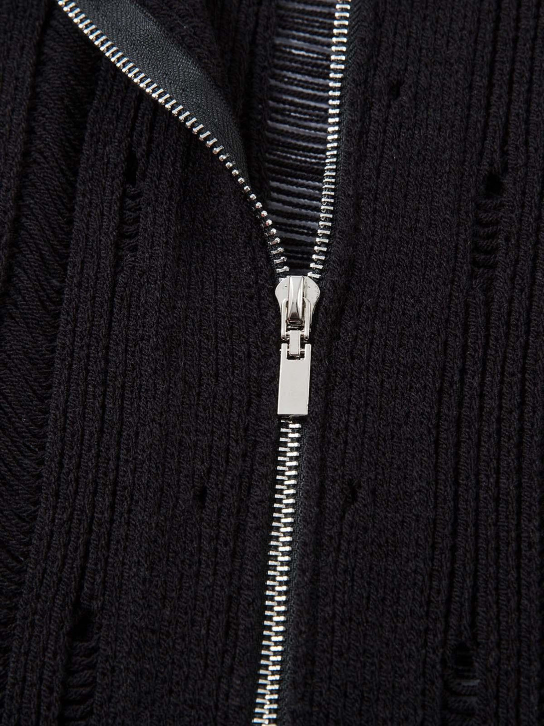 Focusing on the sleek zipper detail of TALISHKO's black knit short-sleeve shirt, highlighting texture.