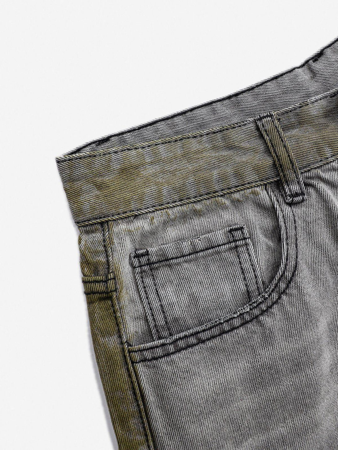 A detailed look at TALISHKO's gray loose jeans, featuring unique color blocking and stitching.
