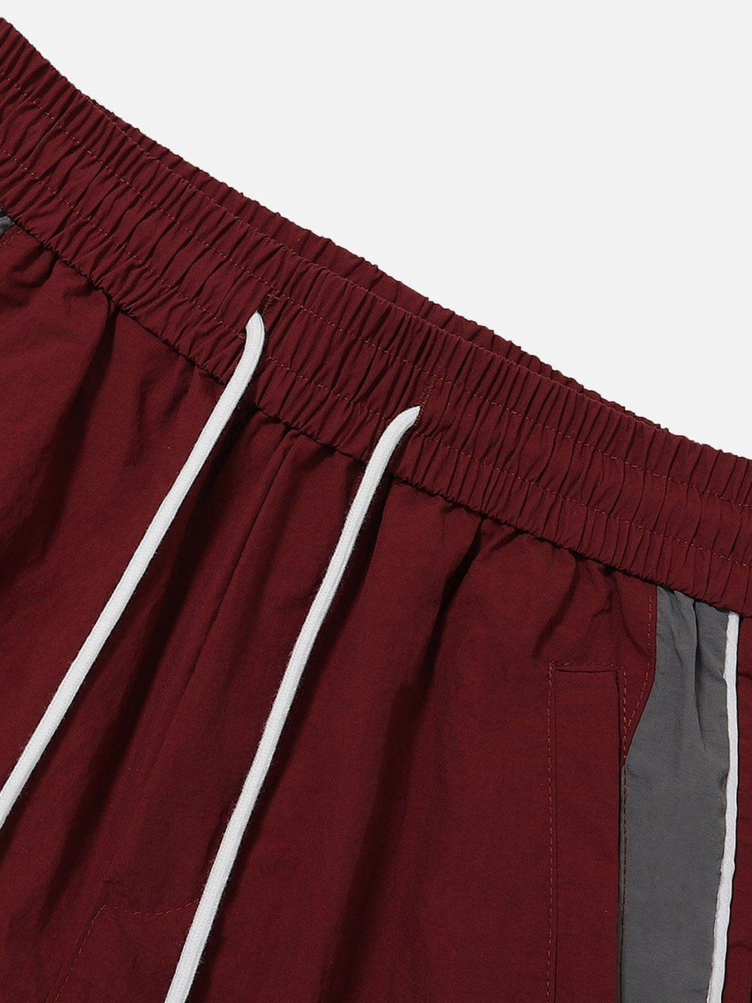 A close-up of TALISHKO burgundy patchwork shorts highlighting the elastic waistband and drawstrings.