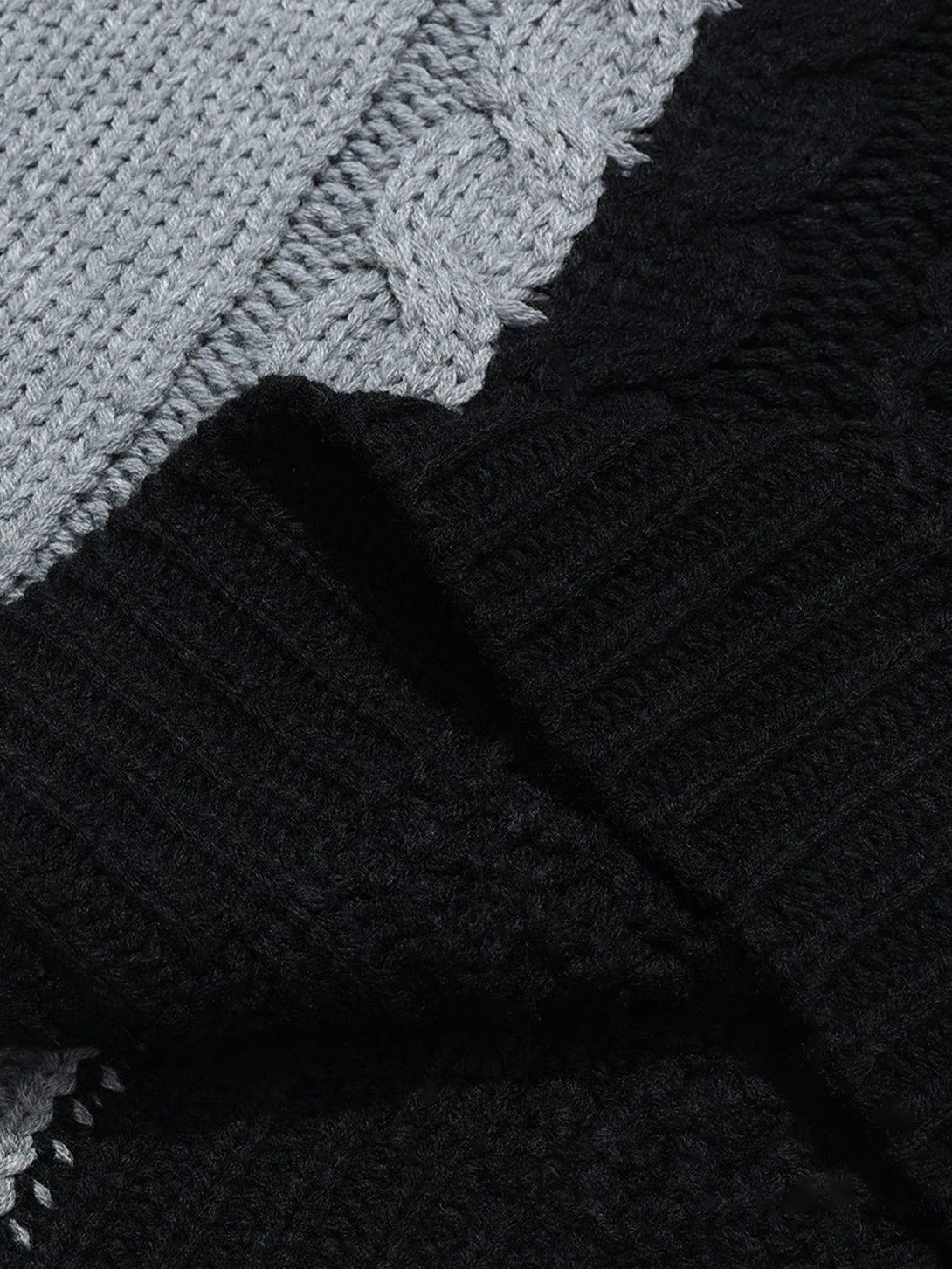 A detailed view of TALISHKO's color-block patchwork sweater showcasing intricate cable knit texture.