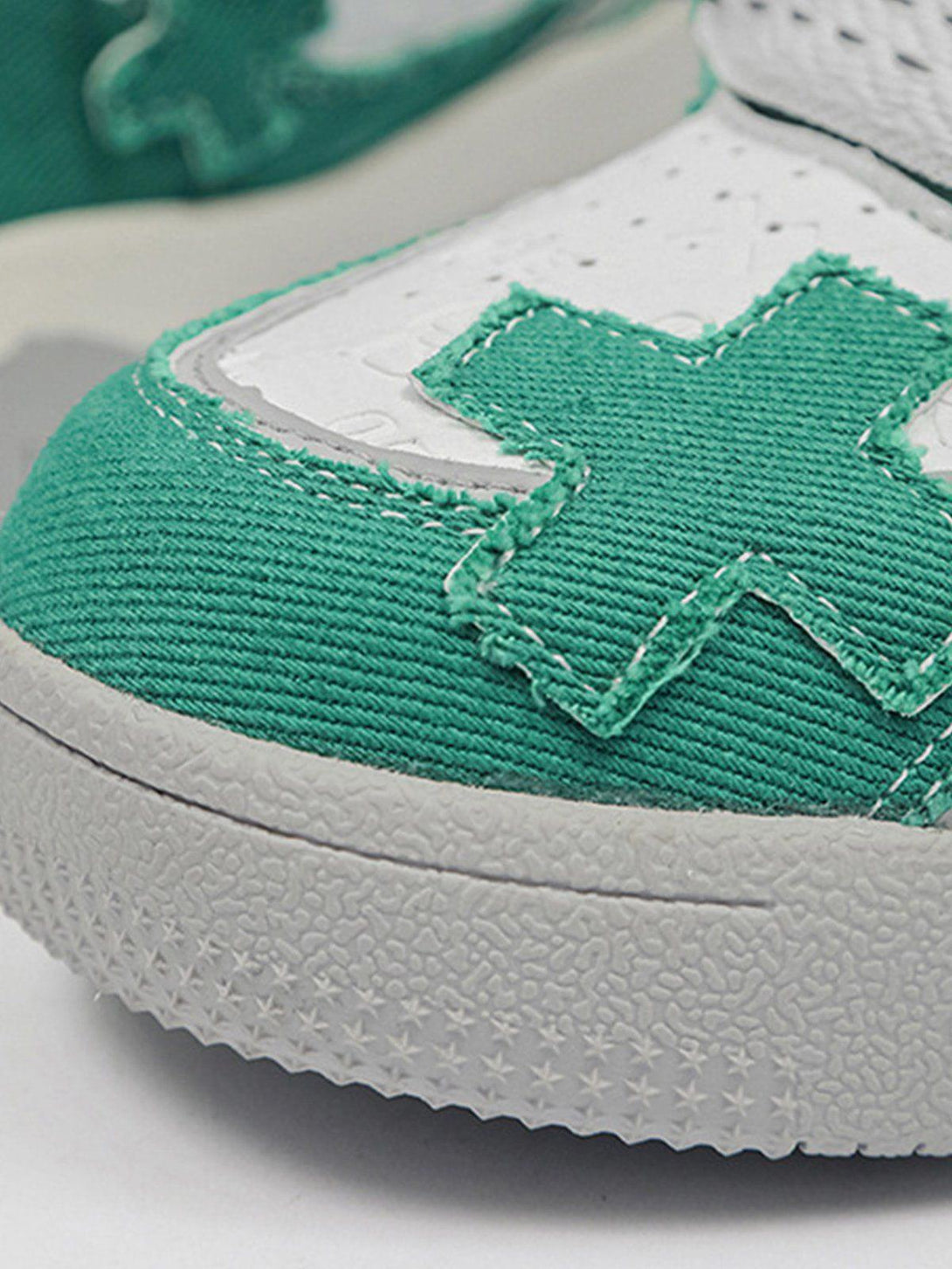 Detailed view of green TALISHKO skate shoes highlighting cross stitching and textured soles.