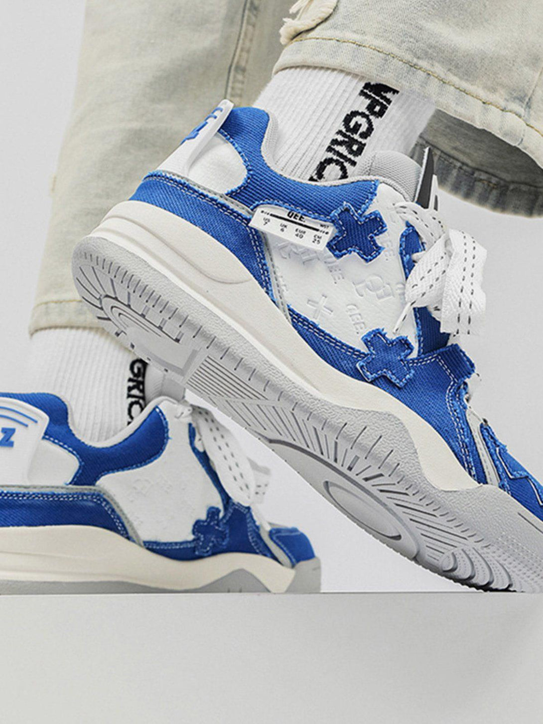 Dynamic side view of blue TALISHKO skate shoes featuring bold cross details and thick soles.