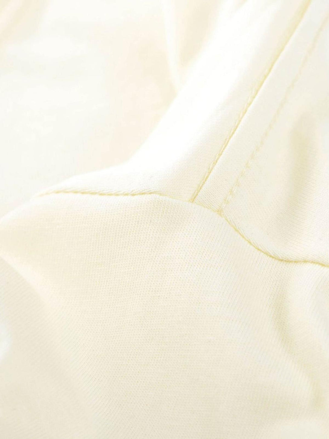A detailed view of TALISHKO's cream T-shirt fabric and stitching, showcasing quality craftsmanship.