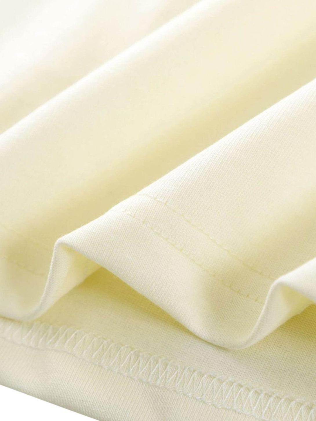 Intricate look at the soft cream fabric and stitching detail of TALISHKO's vibrant T-shirt.