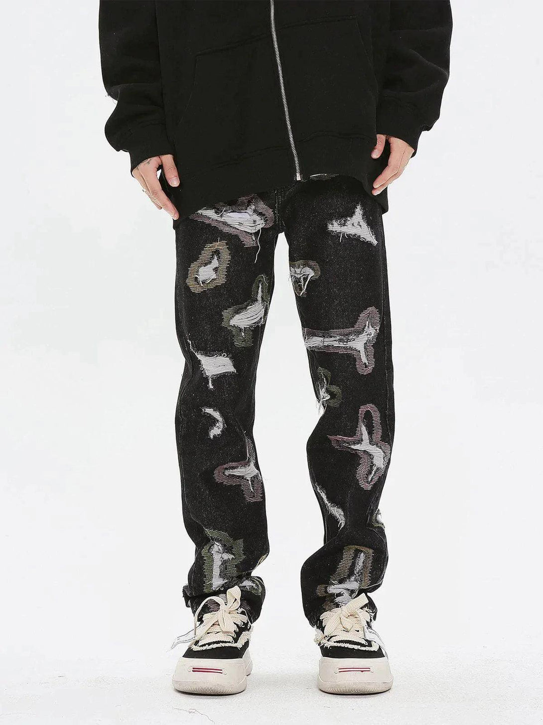 Model wearing TALISHKO colorful hole jeans with abstract patterns and casual sneakers.