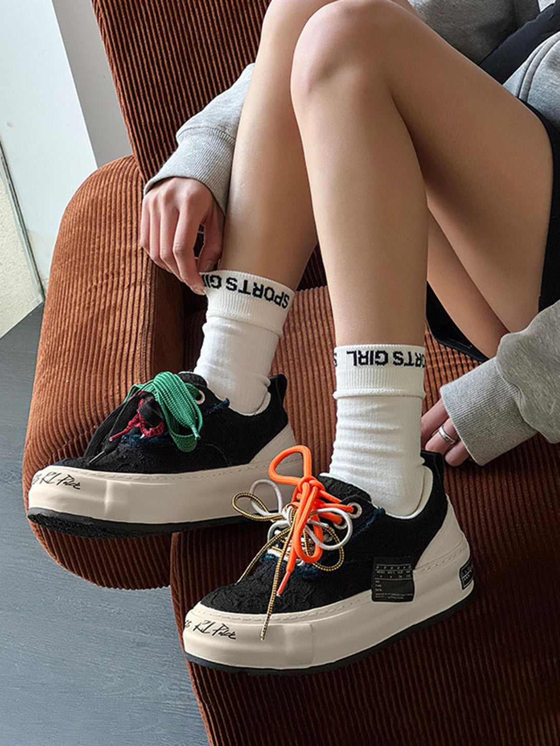 Casual look with TALISHKO sneakers featuring vibrant, mismatched laces, styled with white socks.