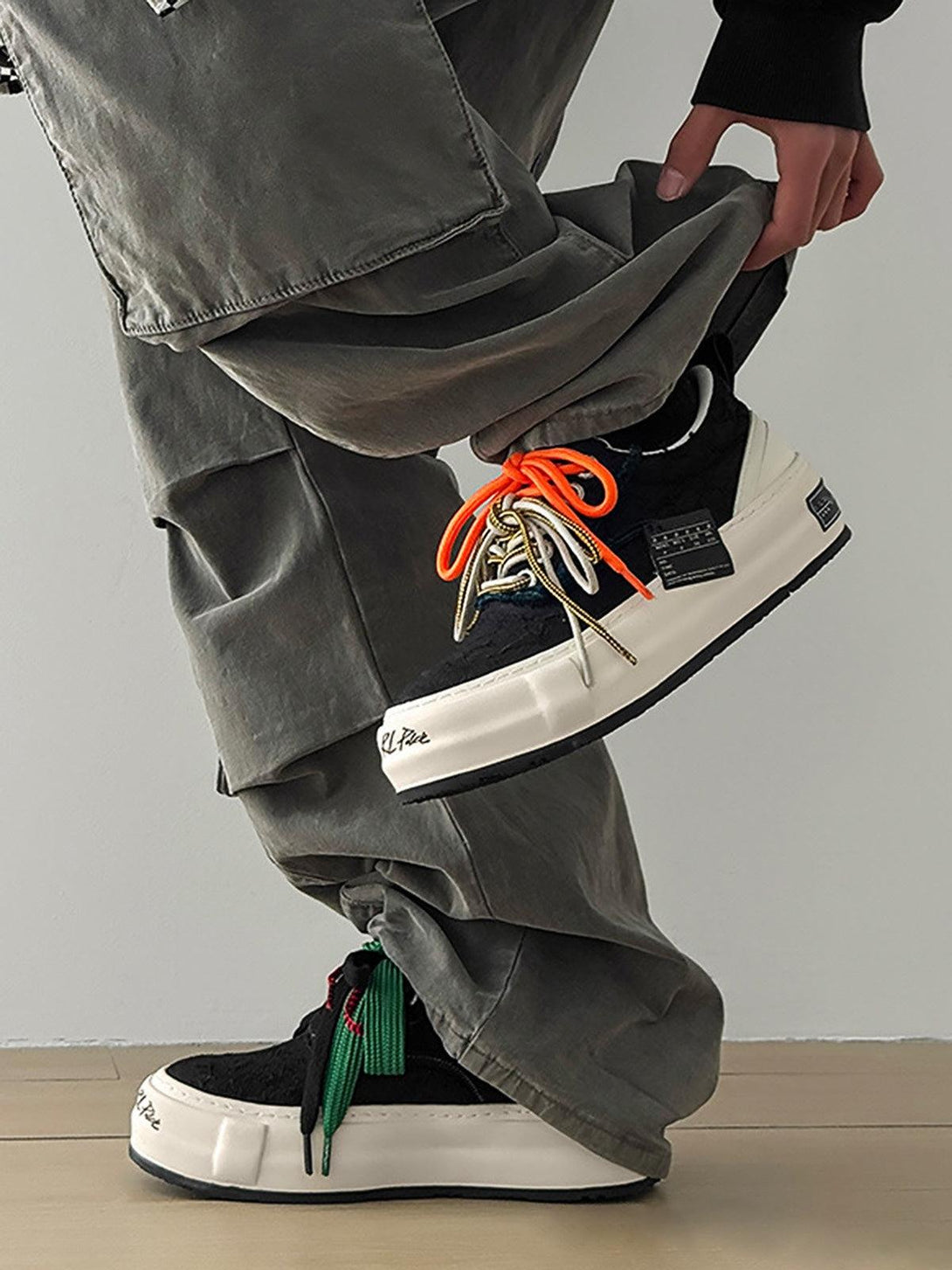 Casual style with TALISHKO sneakers featuring bold, colorful laces and relaxed gray pants.
