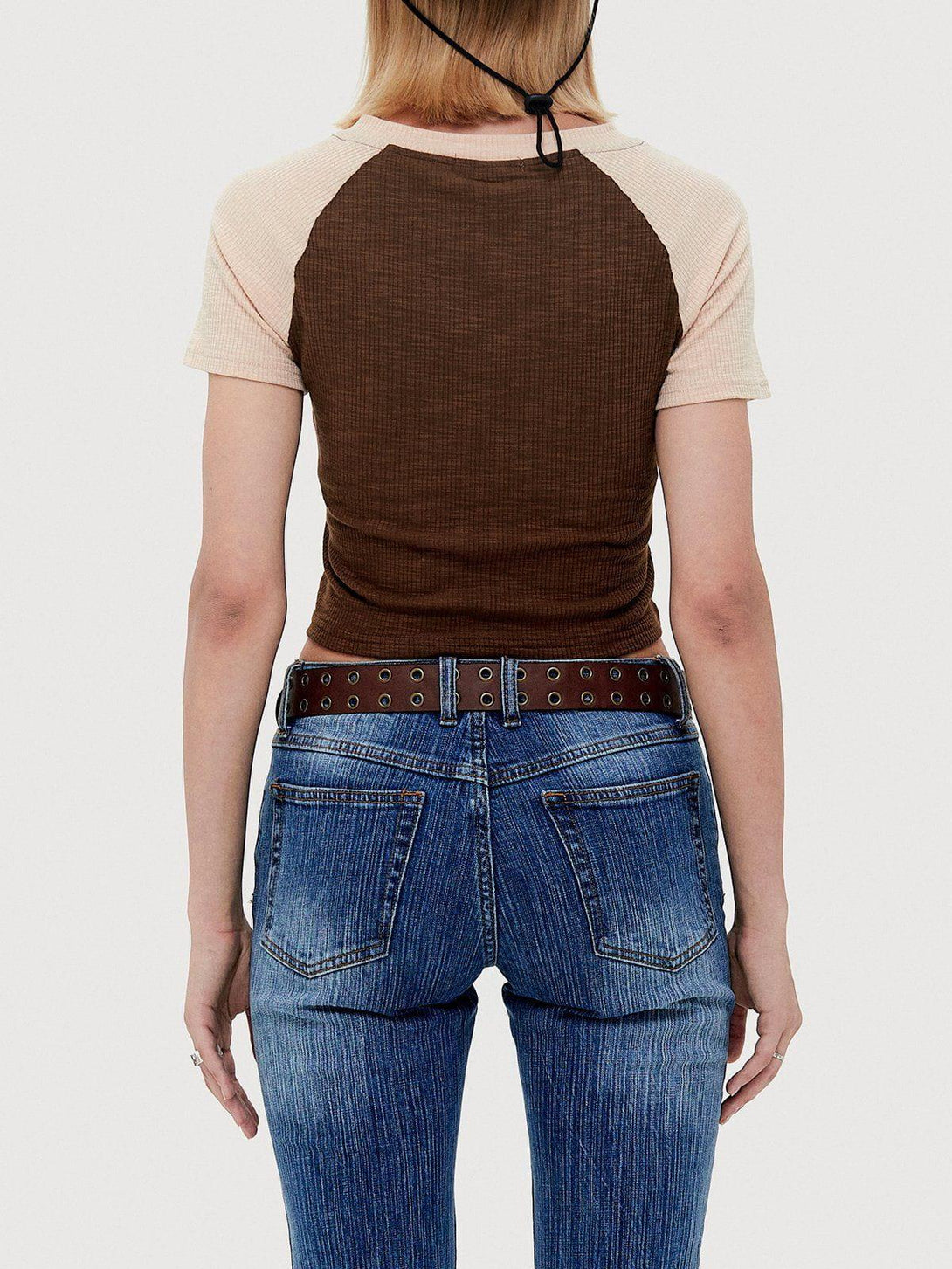 Back view of TALISHKO's color-blocked cropped tee paired with jeans and a studded belt.