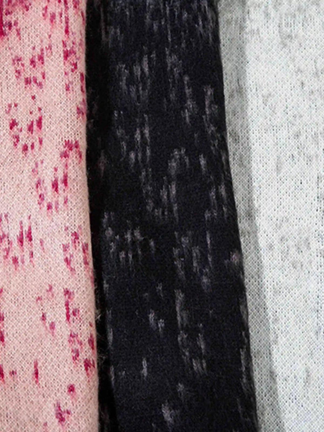 A close-up of TALISHKO sweater fabric showing a unique pink, black, and gray pattern blend.