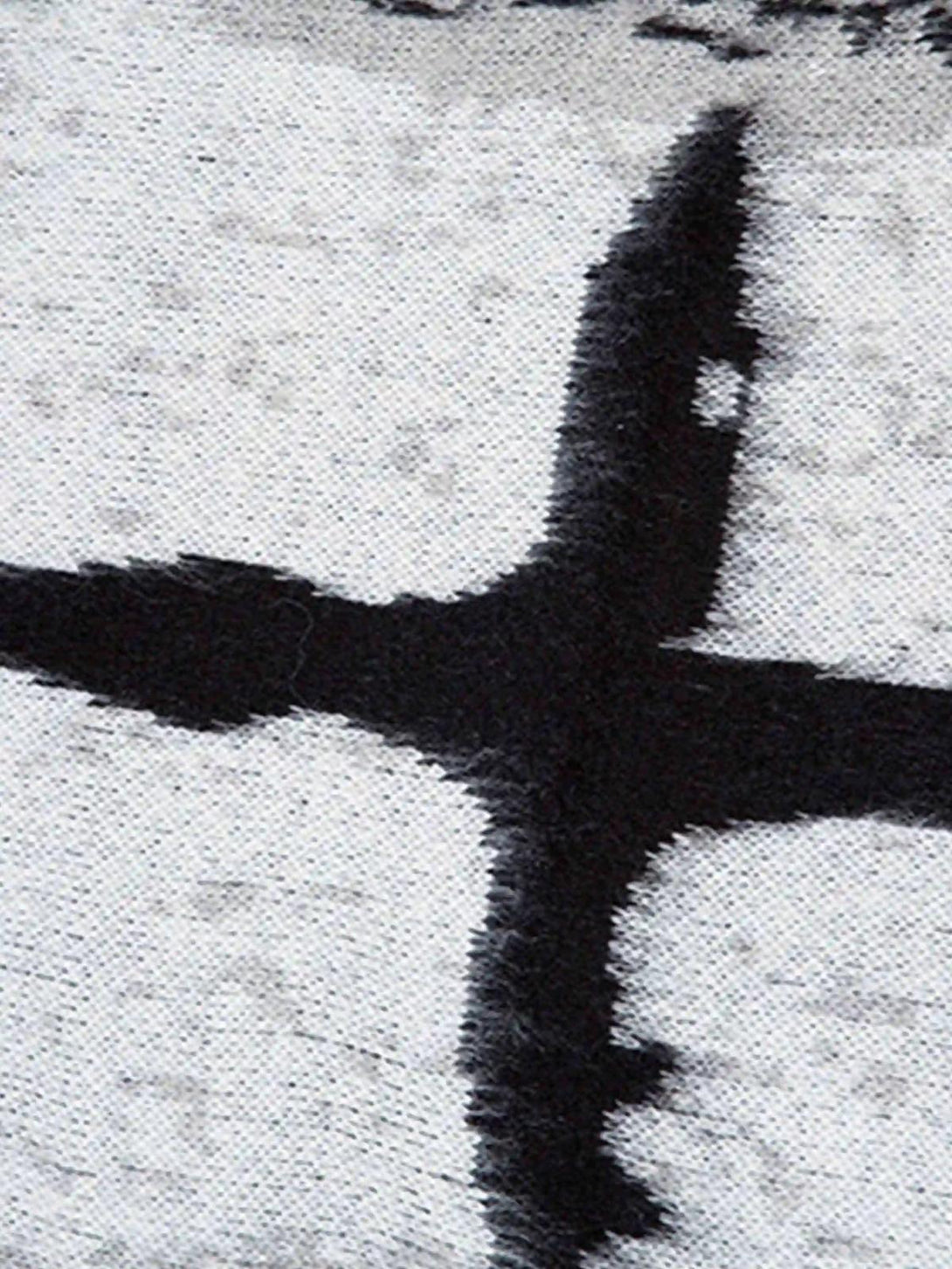 Zoomed-in texture of TALISHKO sweater highlighting a bold black and white cross pattern.