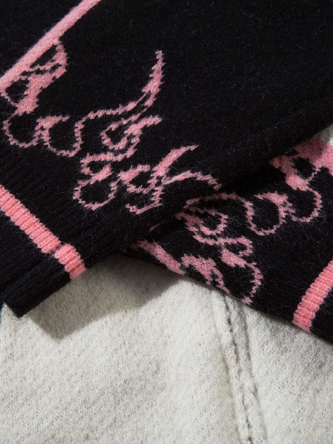 Detailed view of TALISHKO sweater's jacquard texture with pink and black contrast design.