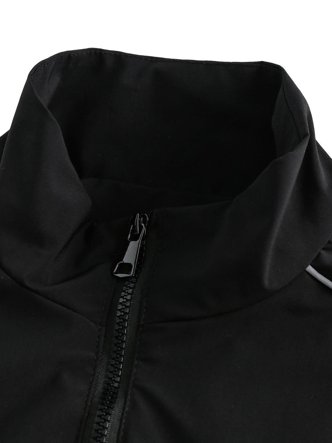 A detailed view of the zipper and collar on a black track jacket by TALISHKO.
