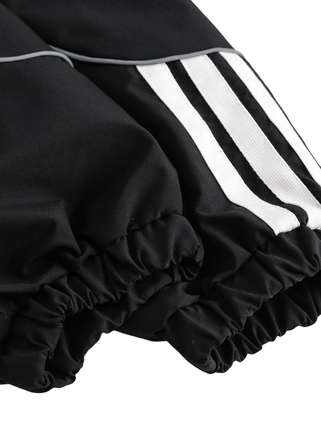 A close-up of the elastic cuffs and contrast white stripes on a TALISHKO track jacket.