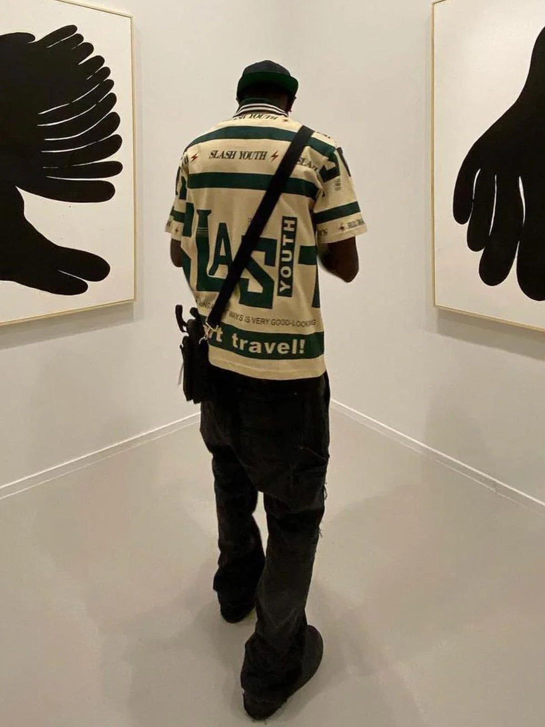 Back view of the TALISHKO contrast polo shirt with bold graphics, worn in an art gallery setting.