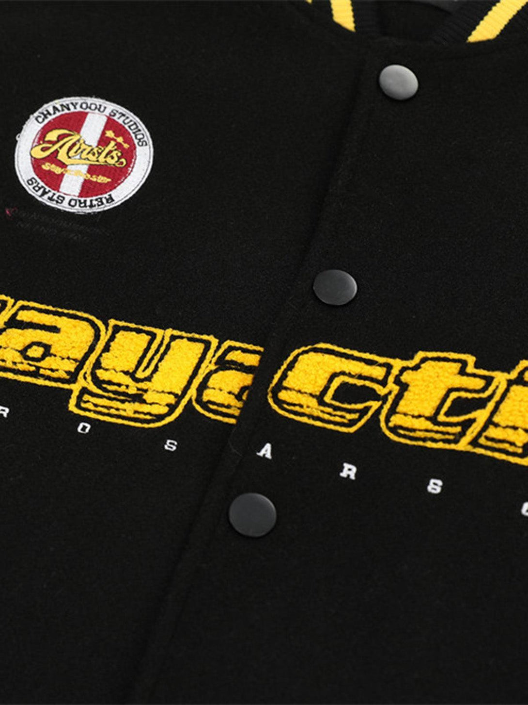 A detailed look at TALISHKO bomber jacket's embroidery and patches on black fabric.
