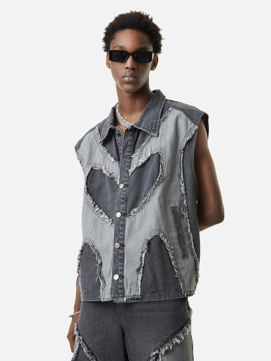 Wearing a TALISHKO denim vest with contrast heart stitching, perfect for sunny days.