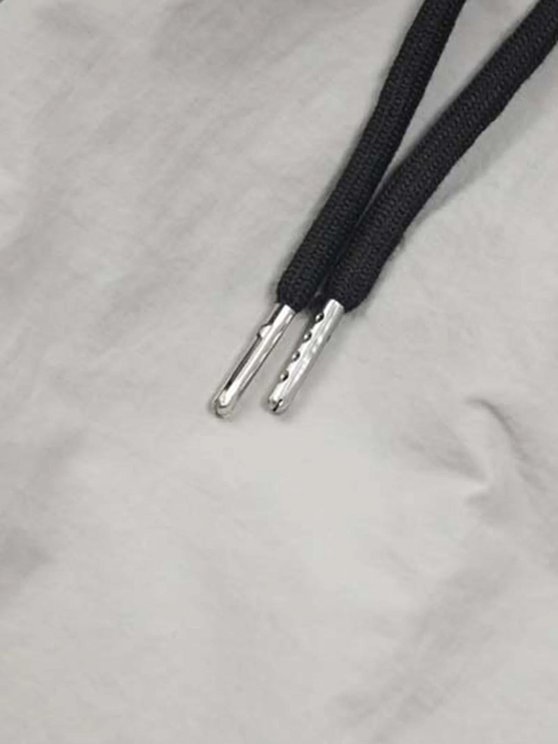 A detailed view of TALISHKO's drawstring ends on sweatpants, showcasing sleek silver tips.