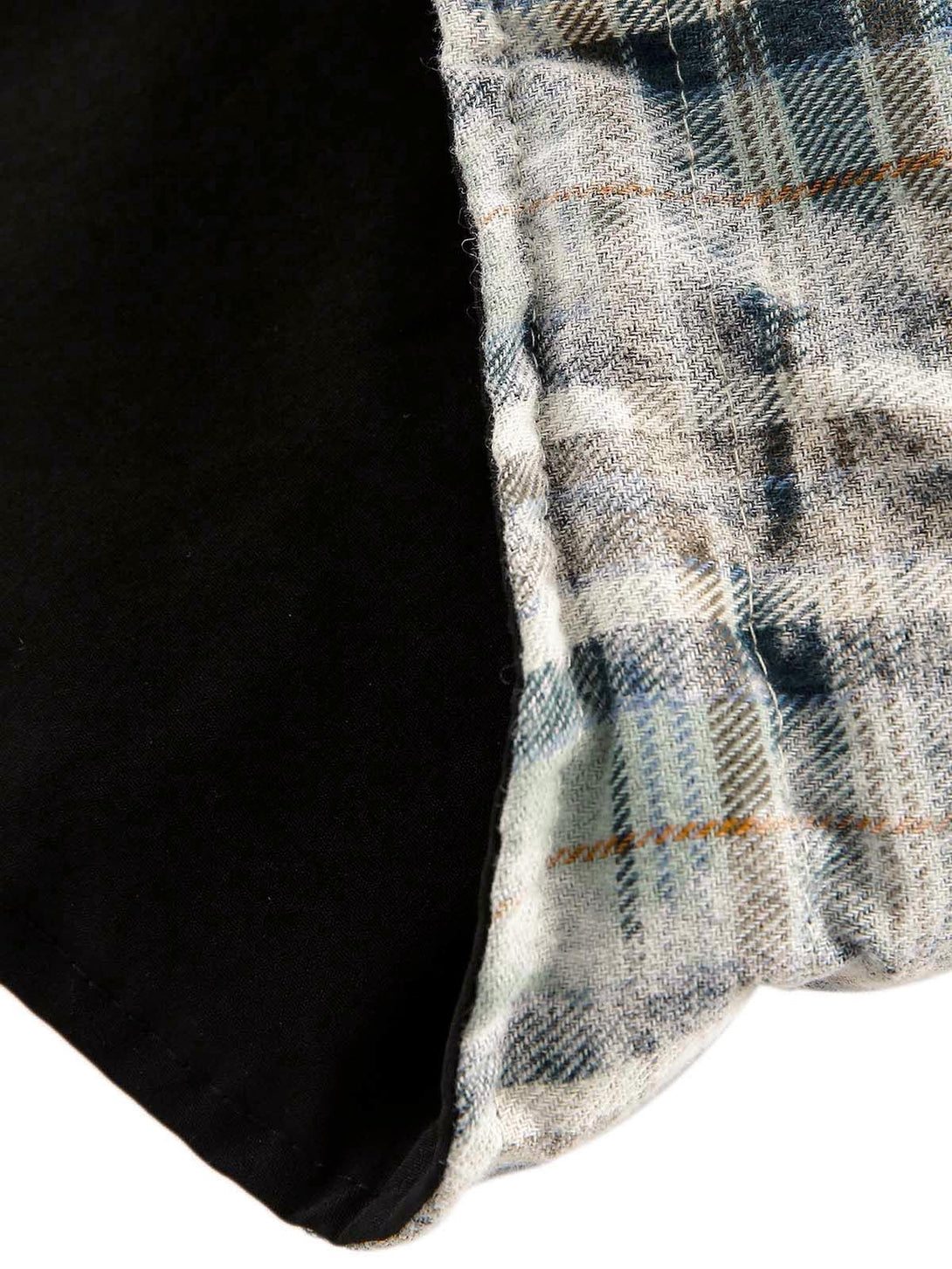 Zoomed-in texture of the TALISHKO reversible jacket, highlighting plaid pattern and black fabric.