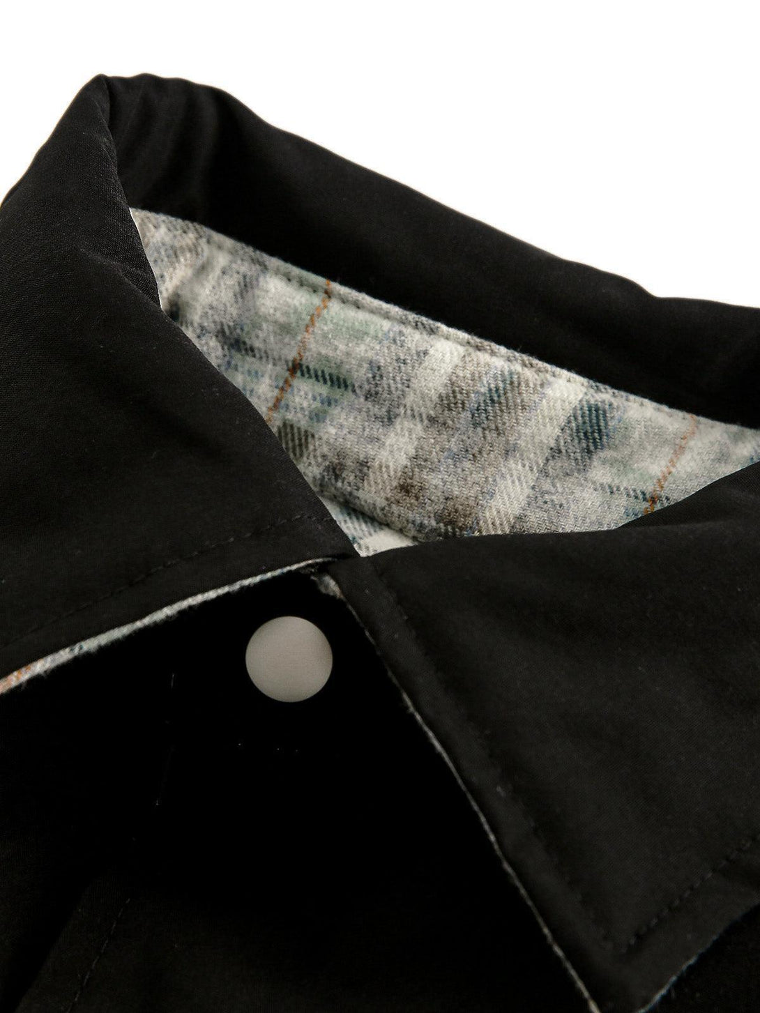 Detail of the TALISHKO reversible jacket collar, showcasing plaid lining and black fabric contrast.