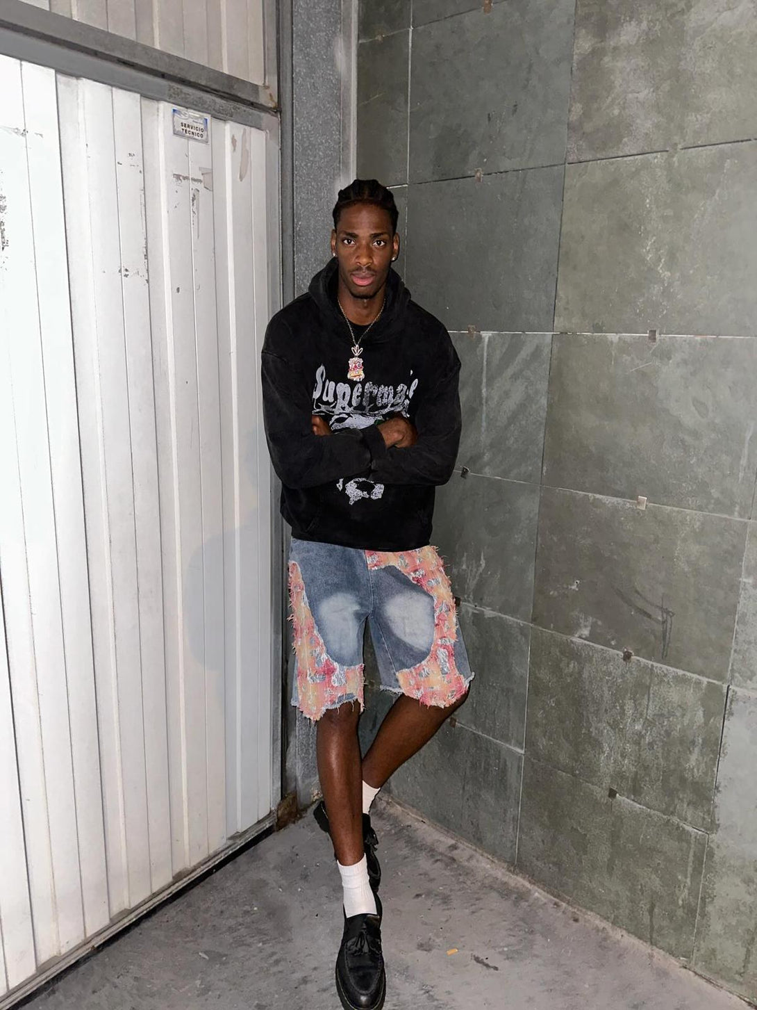 Model wearing TALISHKO ripped floral denim shorts, showcasing casual urban style.