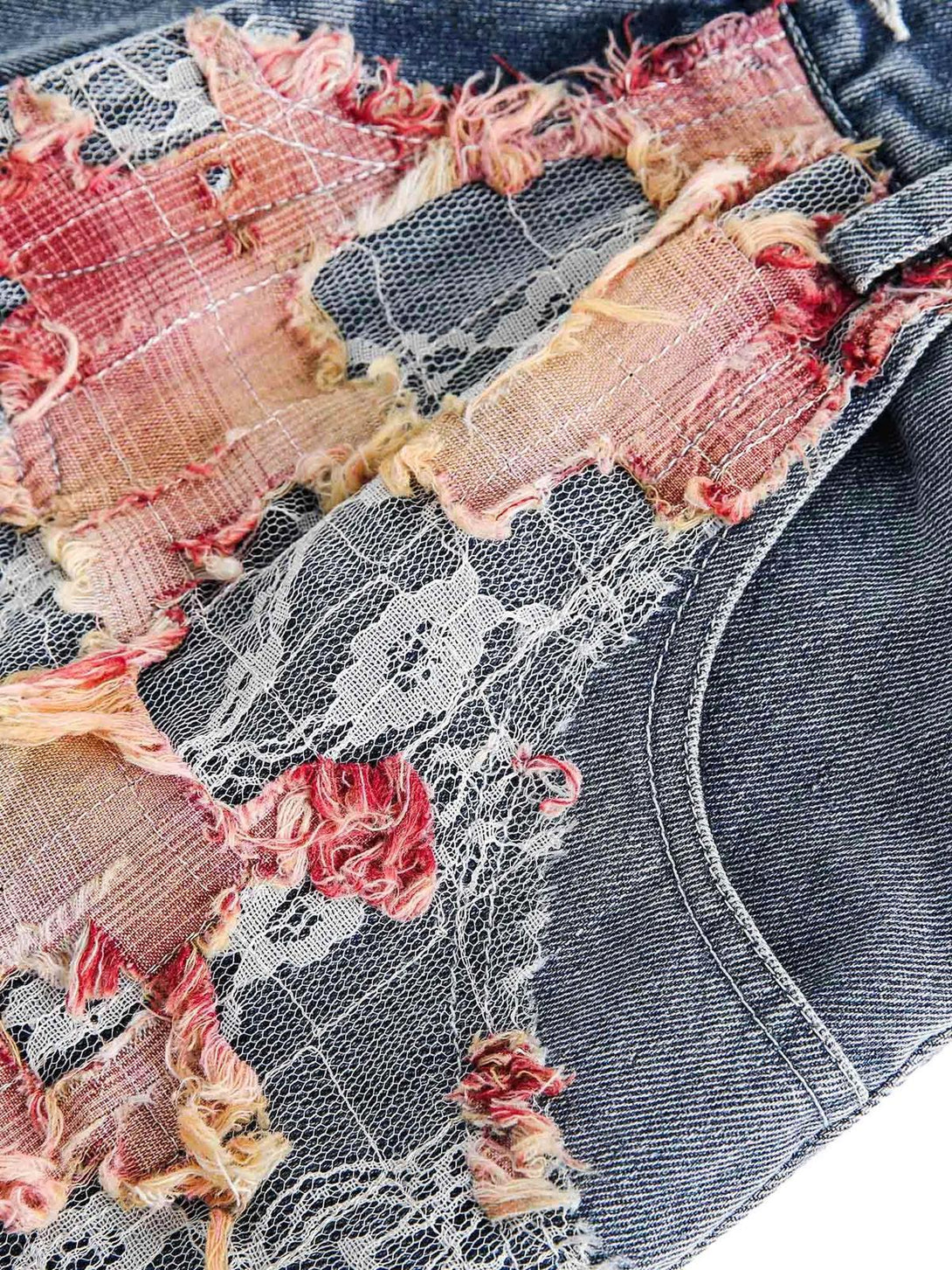 Intricate look at TALISHKO denim shorts featuring ripped floral and lace textures.