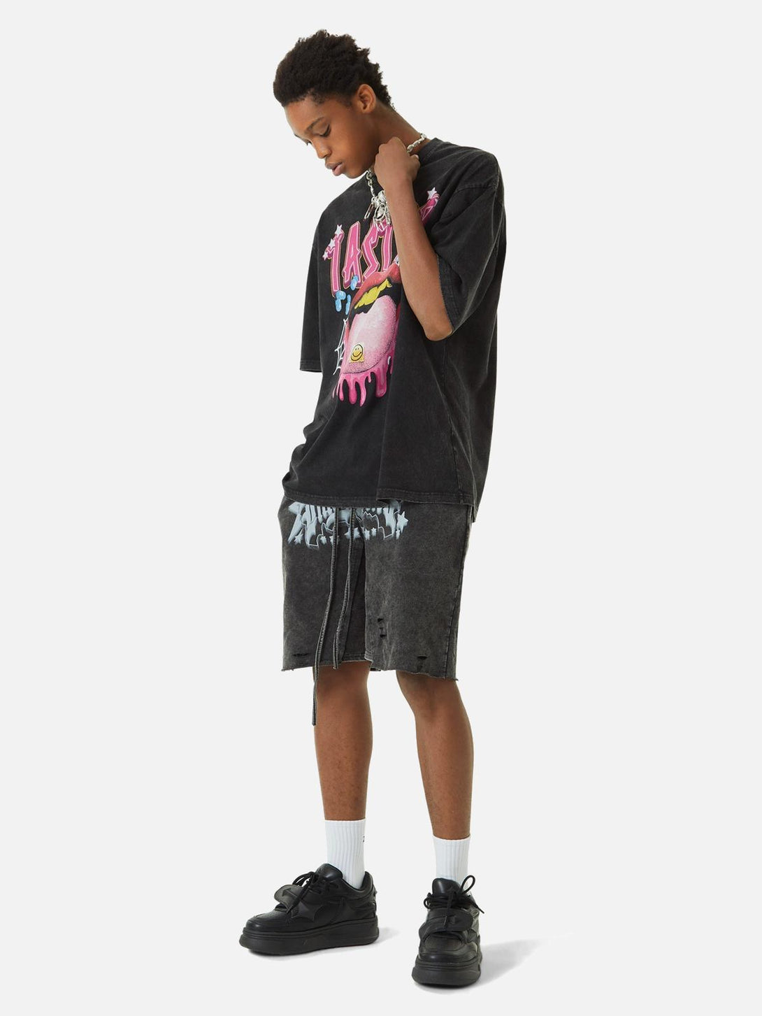 Model wearing TALISHKO T-shirt with a colorful tongue graphic, styled with dark shorts.