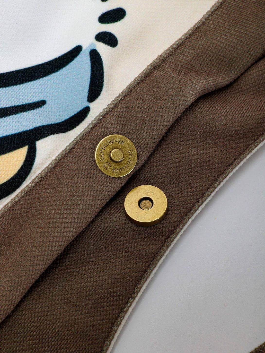 A detailed view of the TALISHKO canvas bag's snap closure, highlighting the playful puppy pattern.