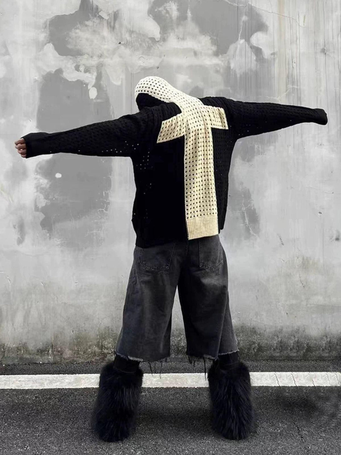 Model wearing a black hooded jacket by TALISHKO with cross jacquard, paired with unique footwear.