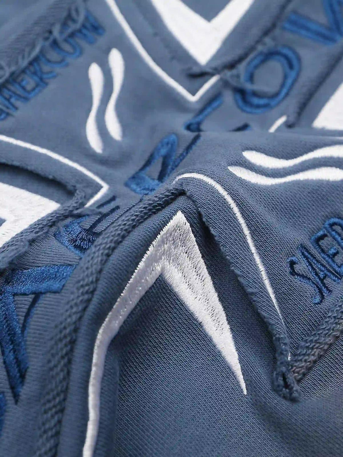 Intricate embroidery detail on a washed hoodie by TALISHKO, featuring cross lettering.