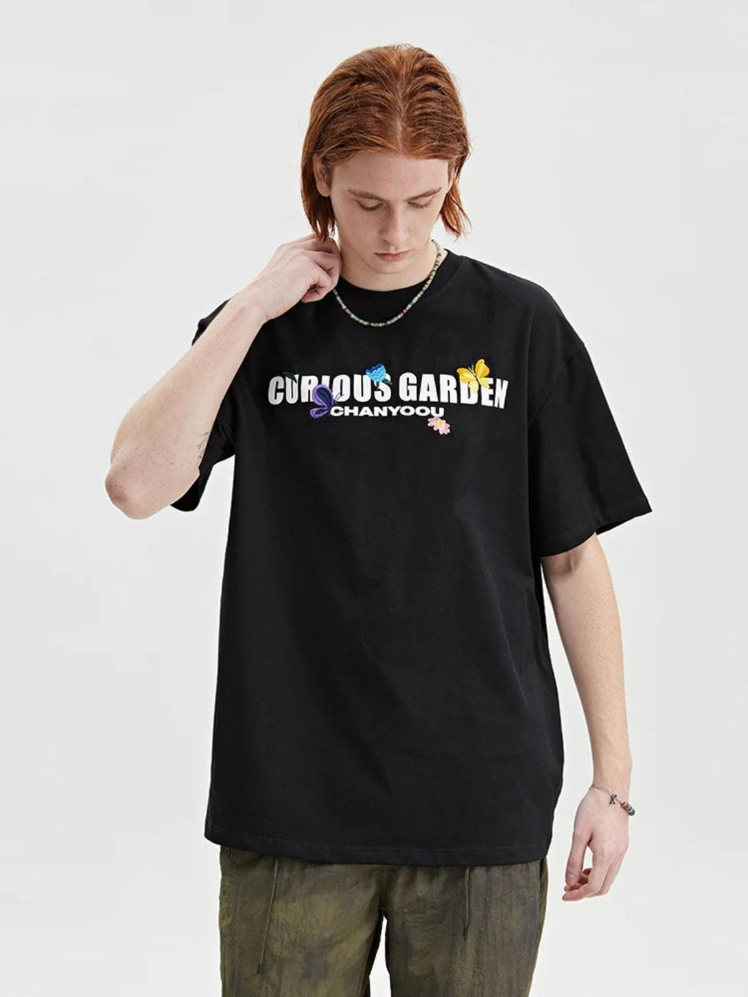 Model in a black TALISHKO tee with colorful embroidery and relaxed fit, ideal for casual wear.