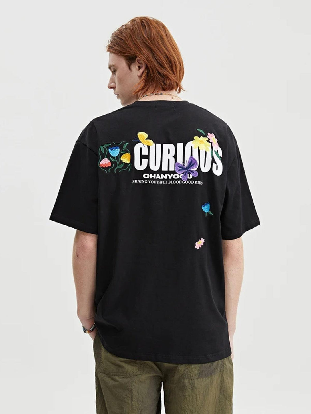 Model wearing a black TALISHKO tee with colorful floral embroidery on the back.