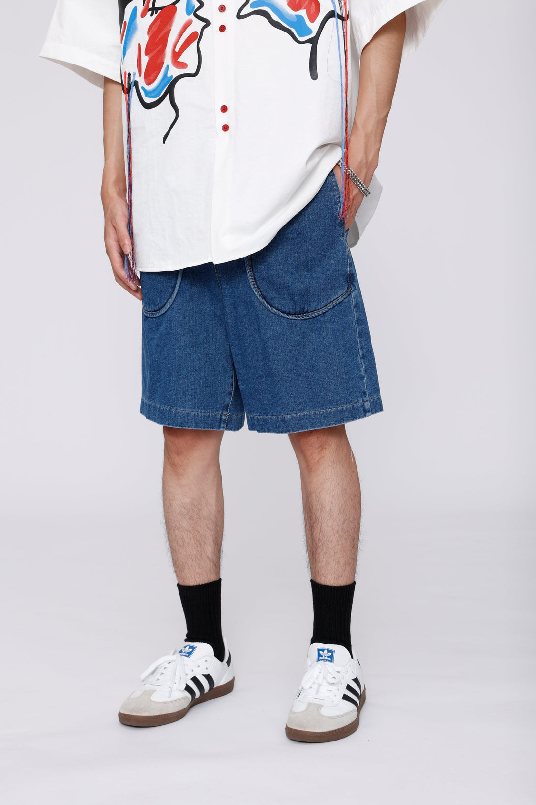 TALISHKO denim jorts with curved pockets styled casually with sneakers and a graphic shirt.