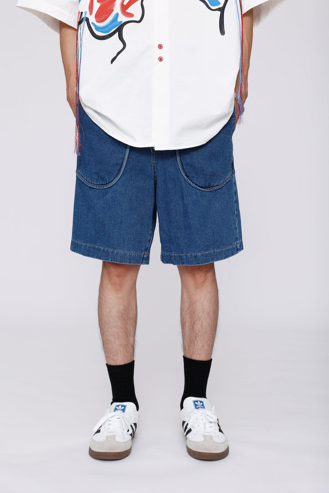 Denim jorts with curved pockets by TALISHKO, front view paired with sneakers and graphic shirt.