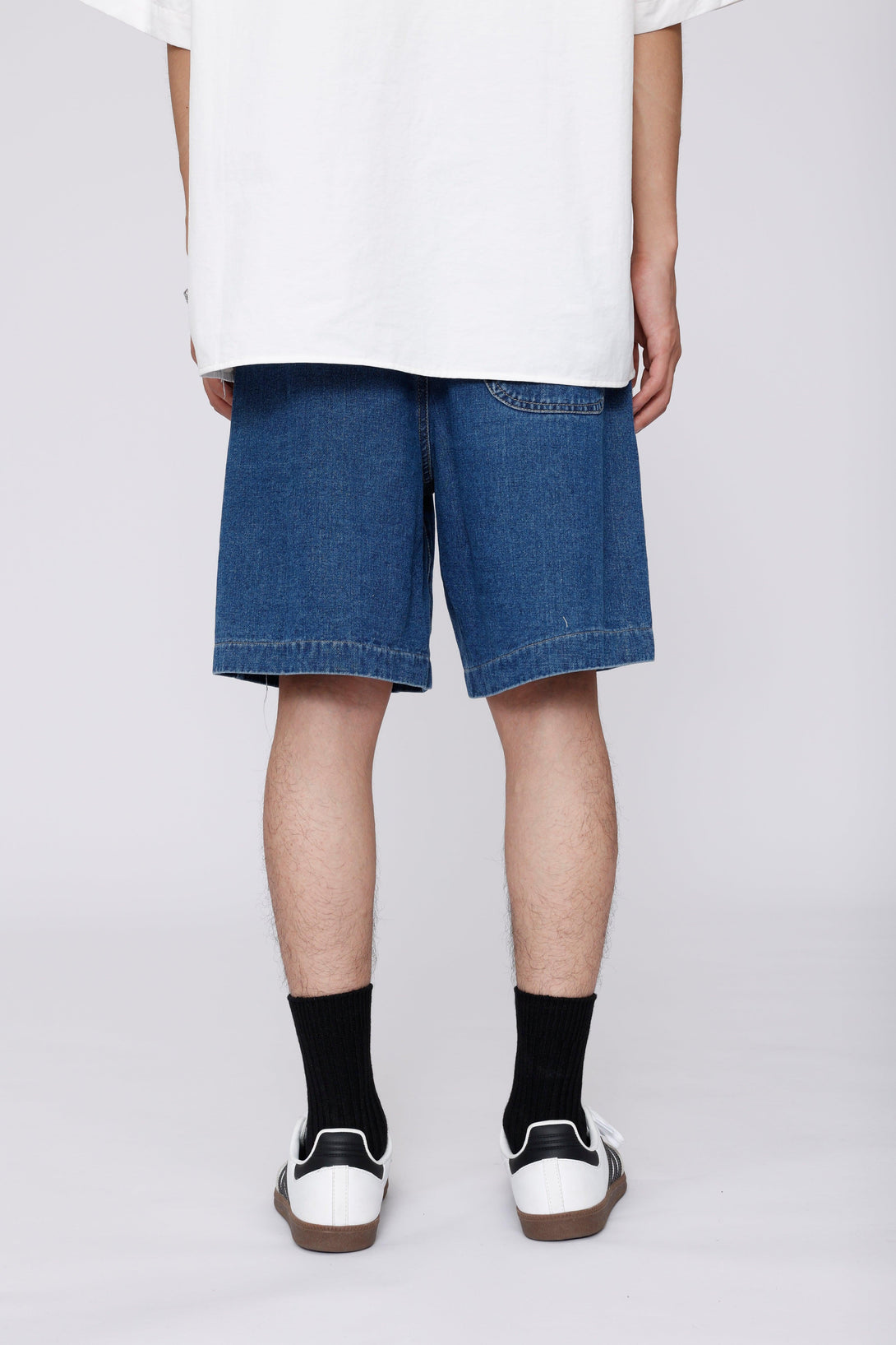 Back view of TALISHKO denim jorts with curved pockets, styled with sneakers for a laid-back vibe.