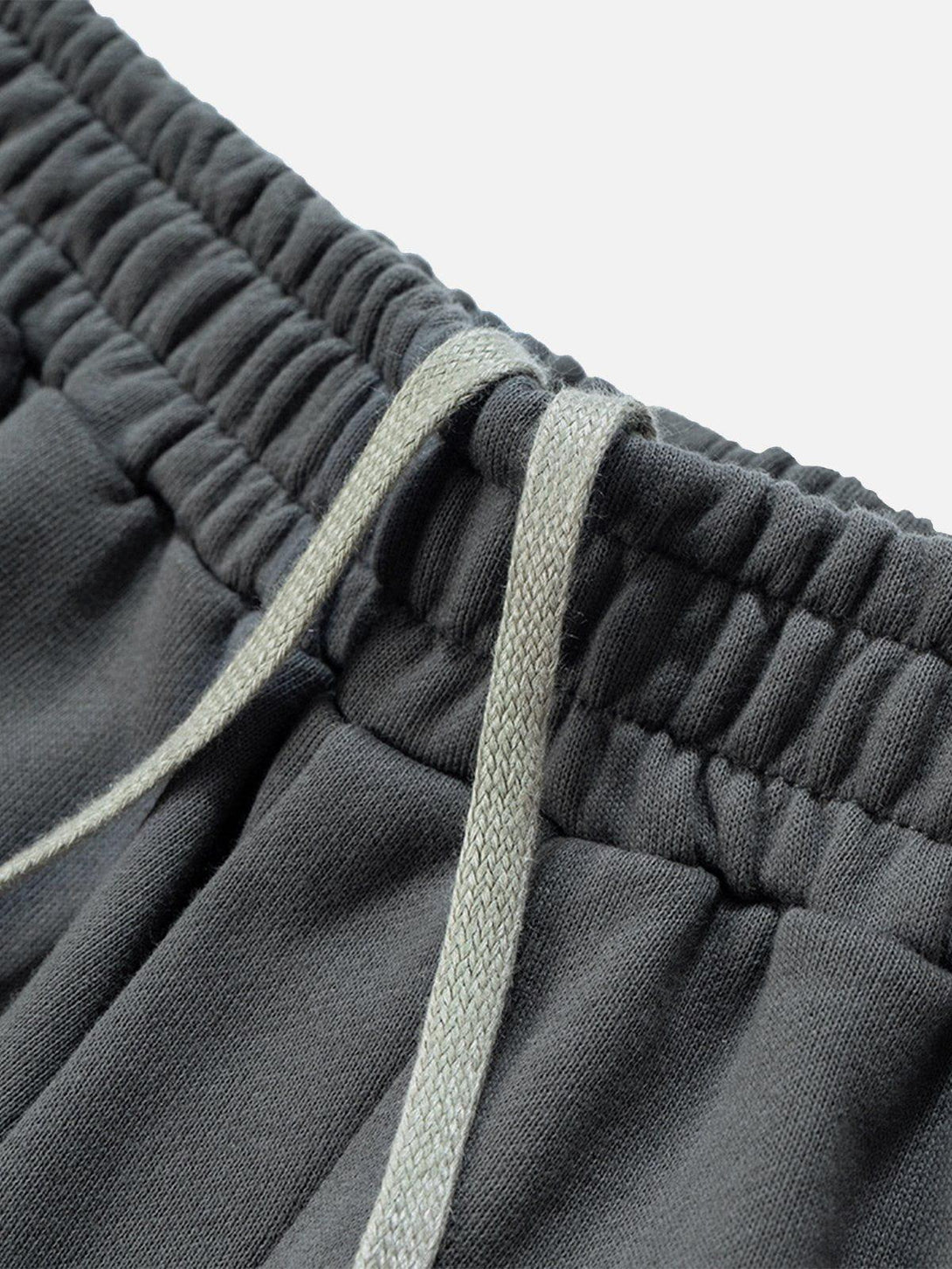 A detailed view of TALISHKO's cut distressed shorts, highlighting the elastic waistband and drawstring.