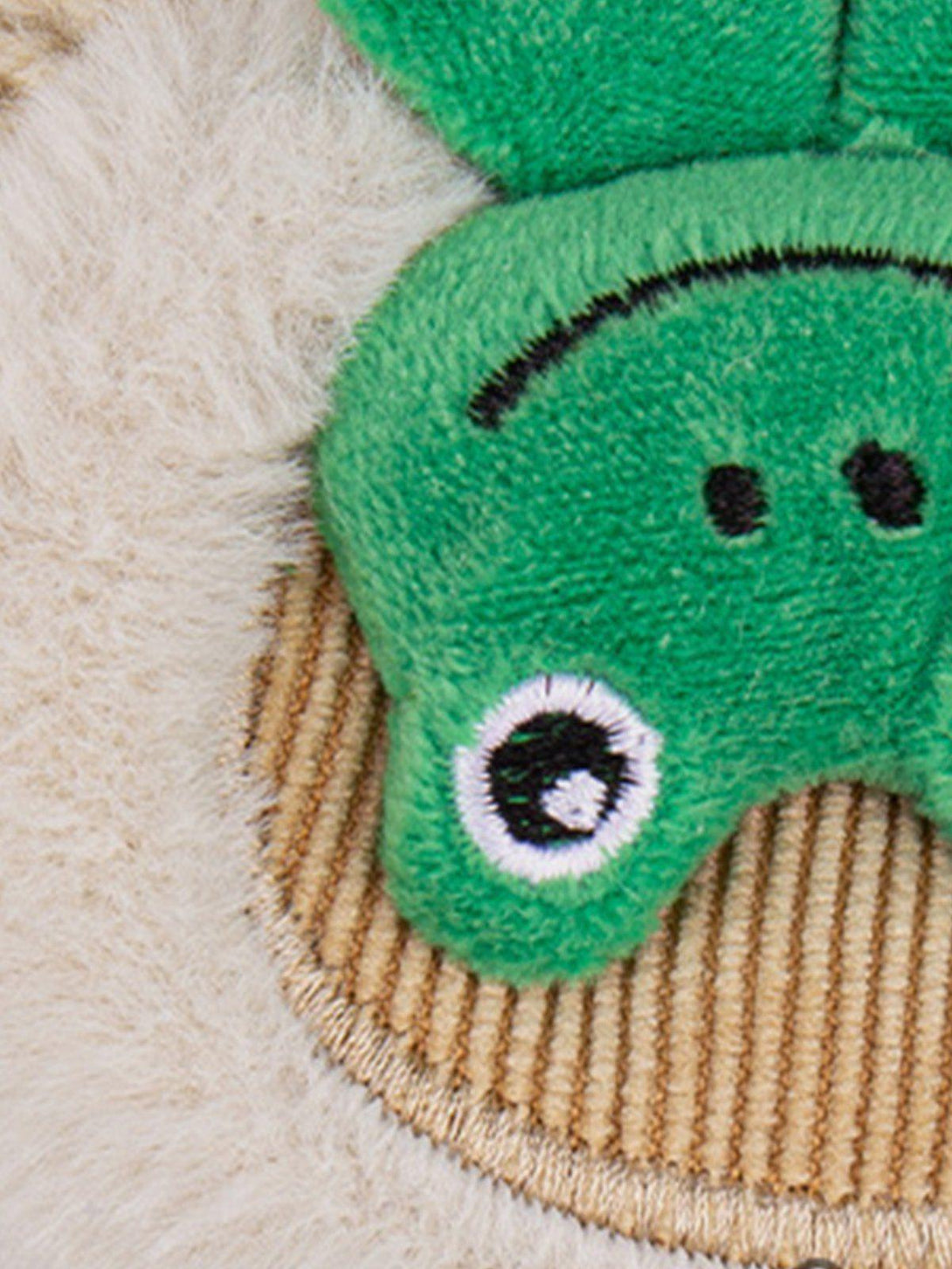 A close-up of TALISHKO's knit hat, highlighting the playful 3D frog detail and texture.