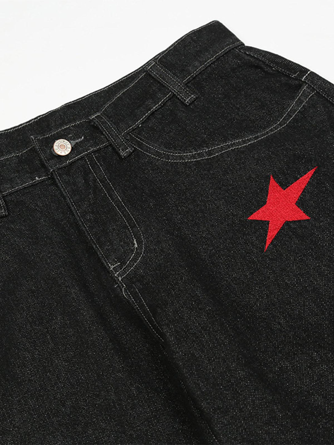 A close-up of TALISHKO's dark gothic jeans highlighting the red embroidered star detail.
