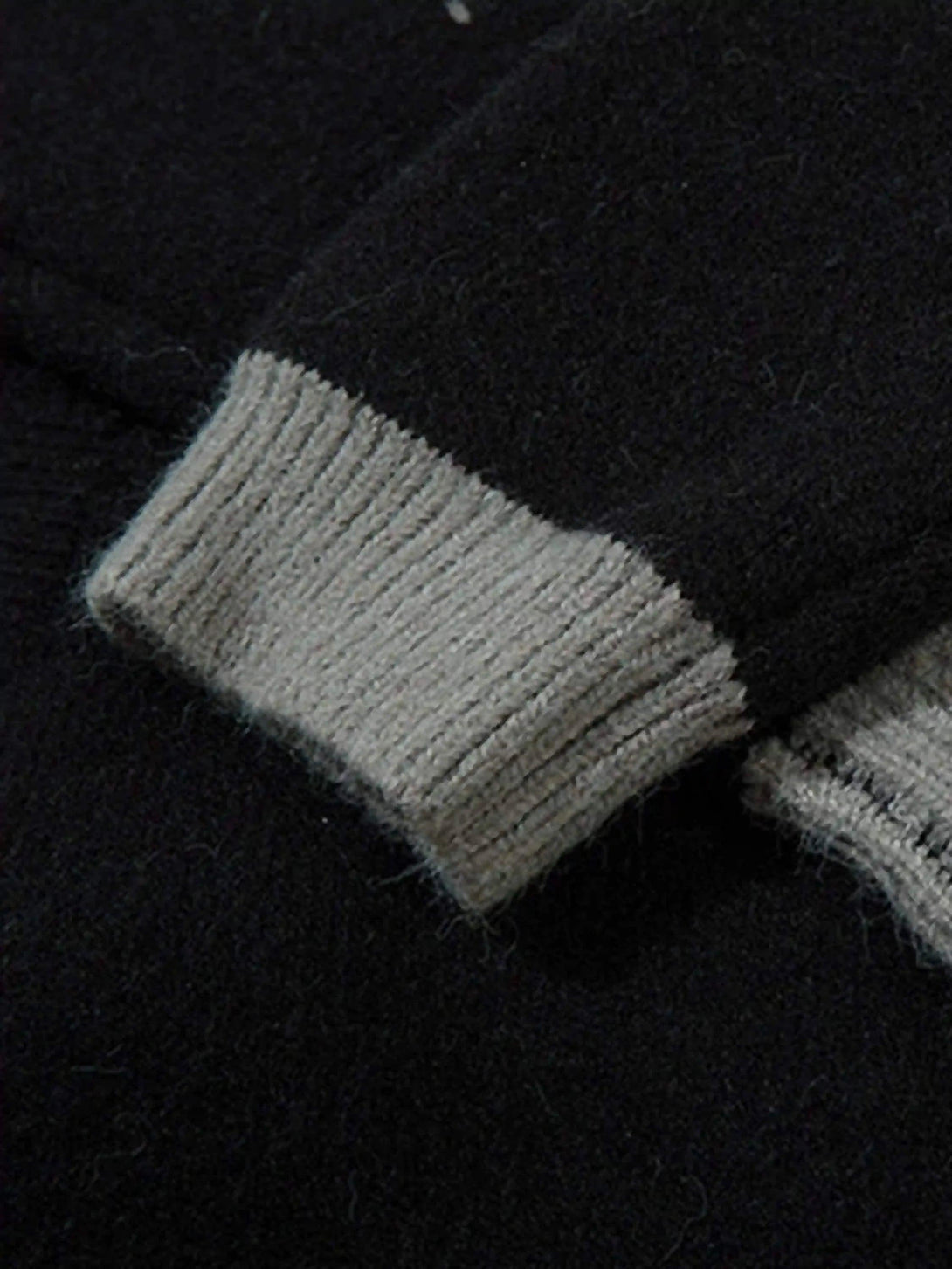 Gray ribbed cuffs on a dark cardigan highlight the intricate design by TALISHKO.