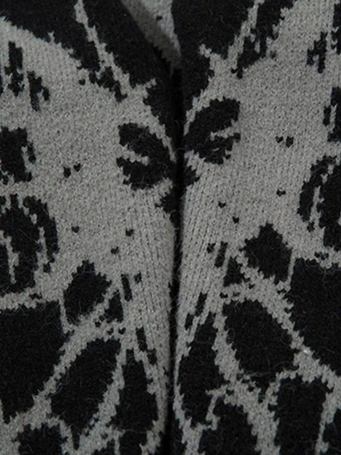 Intricate look at the black and gray spider web pattern on a cardigan by TALISHKO.