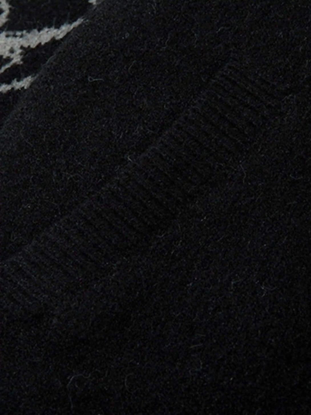 "Focusing on the texture and pattern of a dark cardigan with intricate details by TALISHKO."