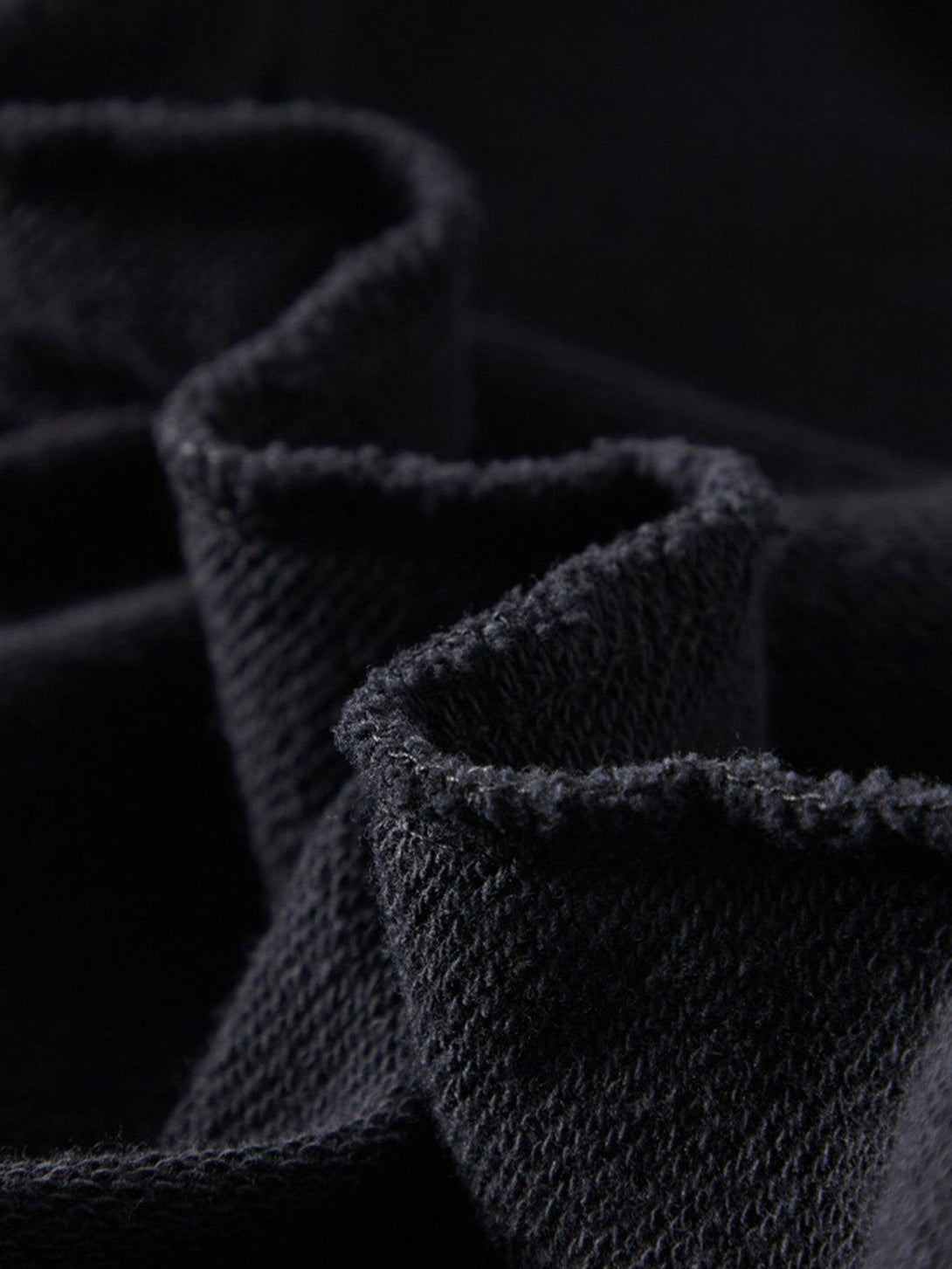 Zoomed-in texture of TALISHKO's dark loose sweatshirt, highlighting its soft, cozy knit fabric.