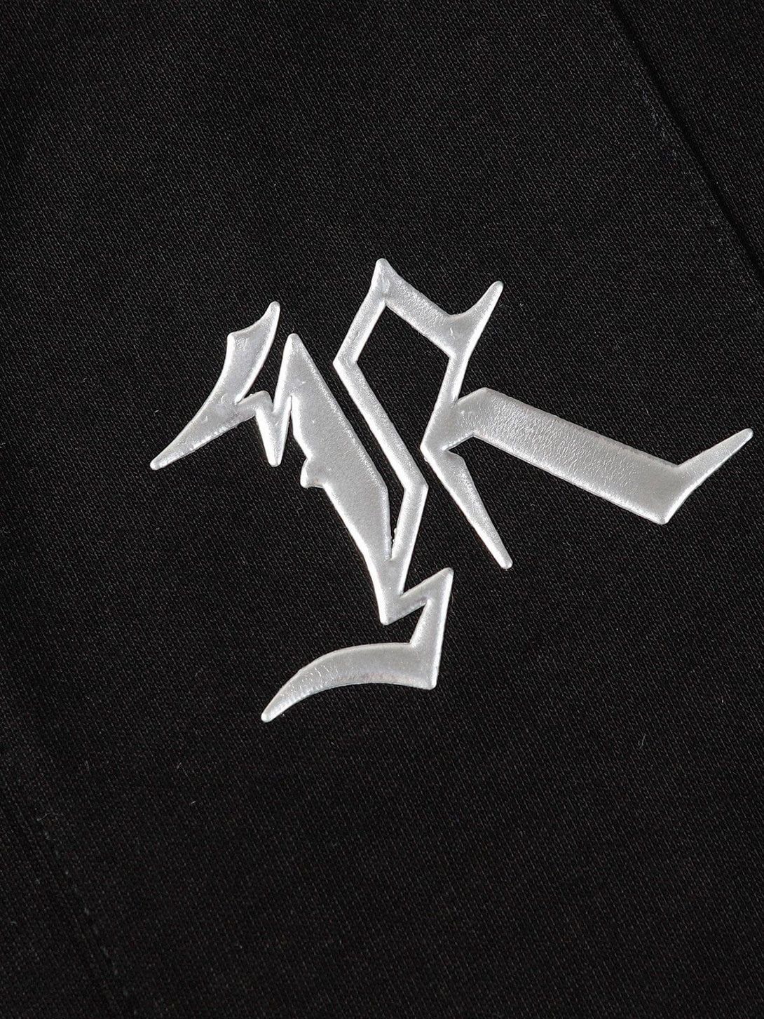 Intricate look at the TALISHKO Deconstruct Rivet Tee, showcasing bold graphic elements on black fabric.