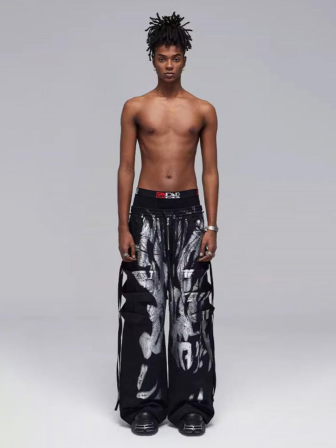 TALISHKO's deconstructed pants feature a striking silver pattern, modeled for a bold look.