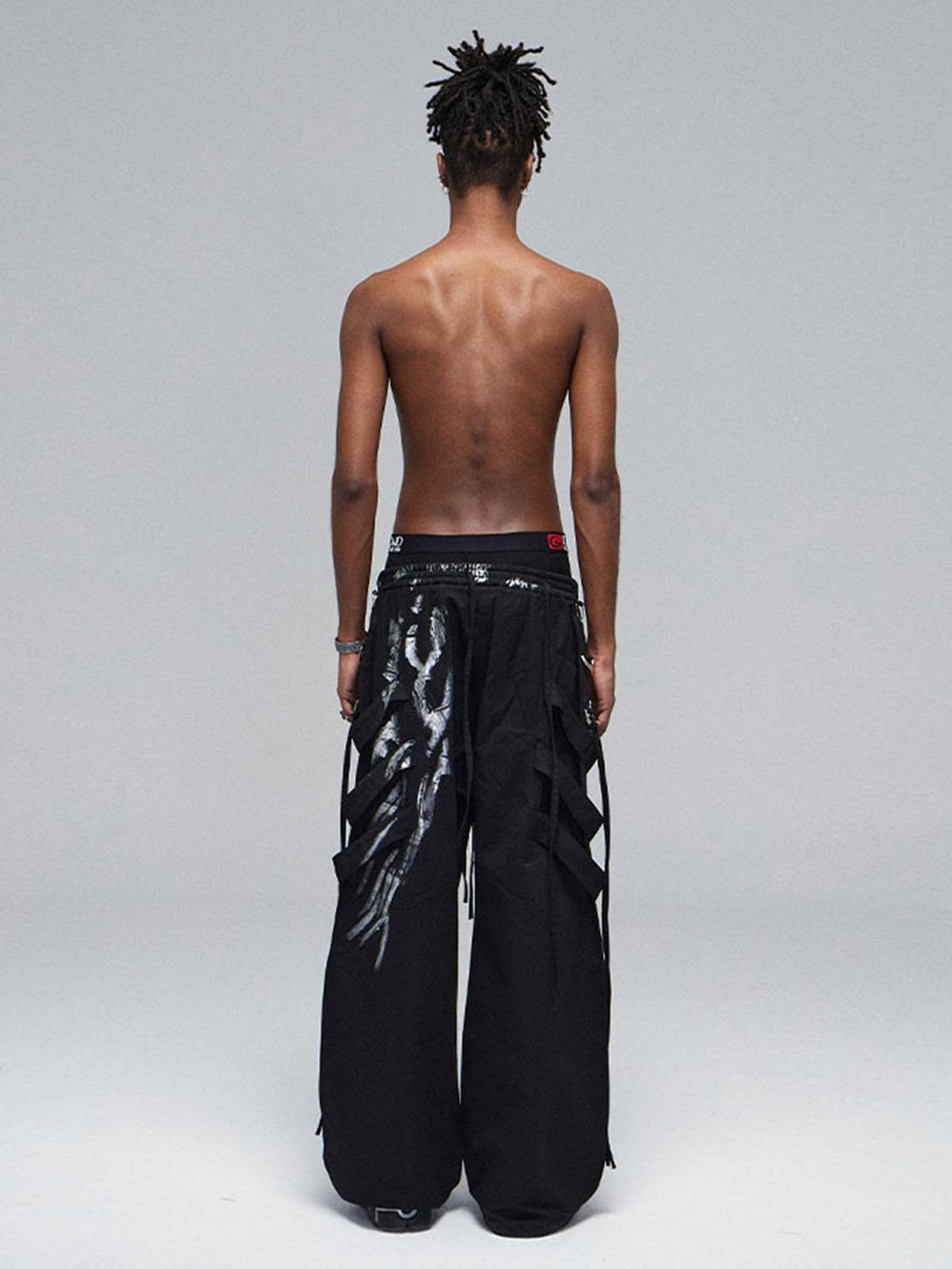 Model wearing TALISHKO's deconstructed pants, showcasing silver ribbon detailing from the back.