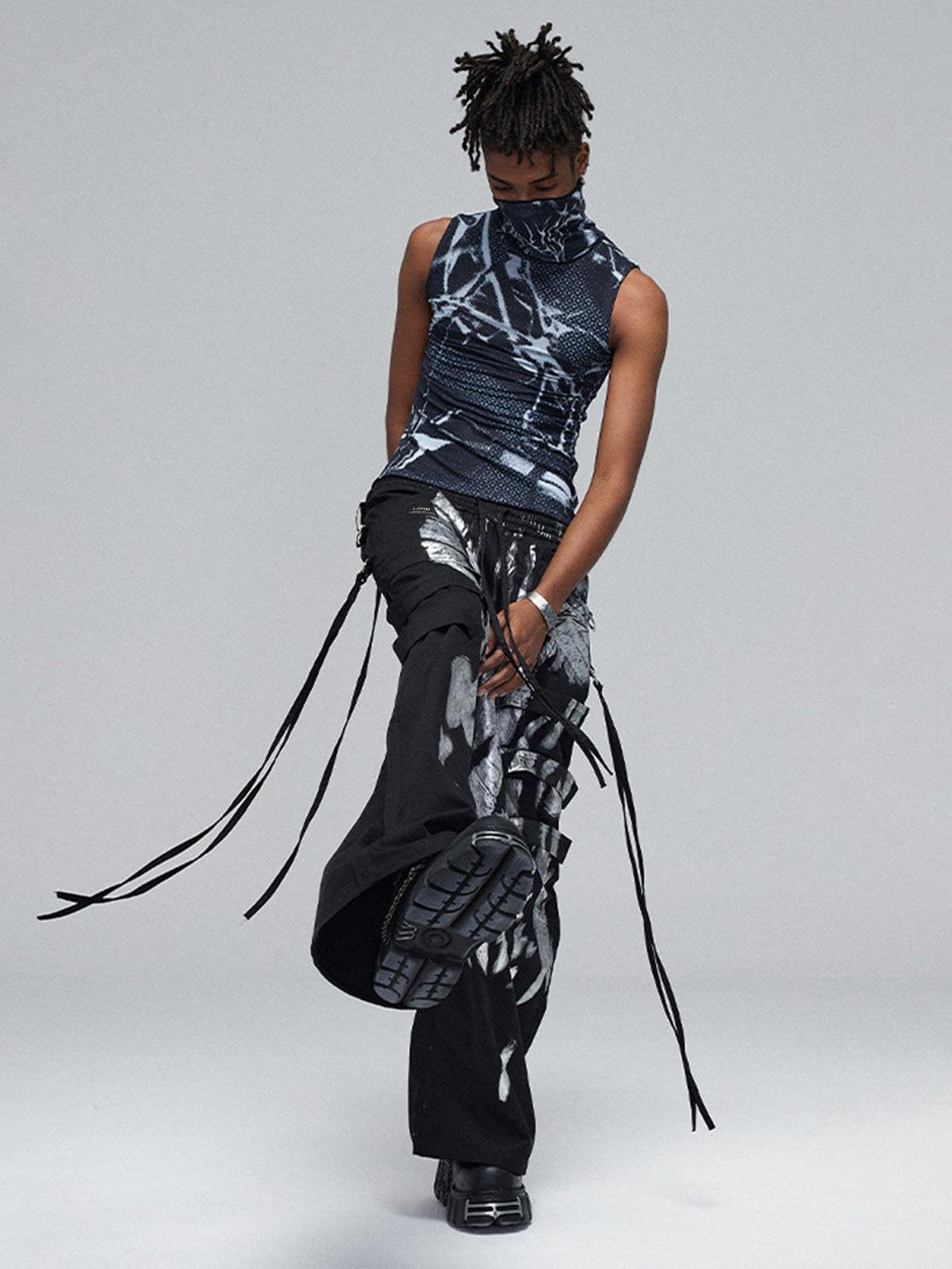 Model in TALISHKO's deconstructed pants with silver ribbon details, striking an urban pose.