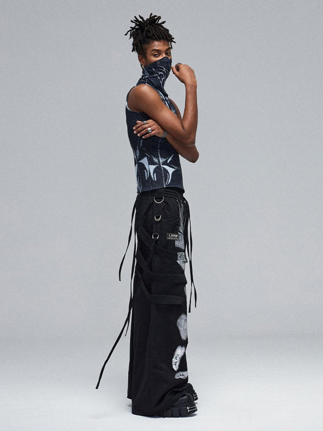 Side view of model wearing TALISHKO's black deconstructed pants with brushed silver details.