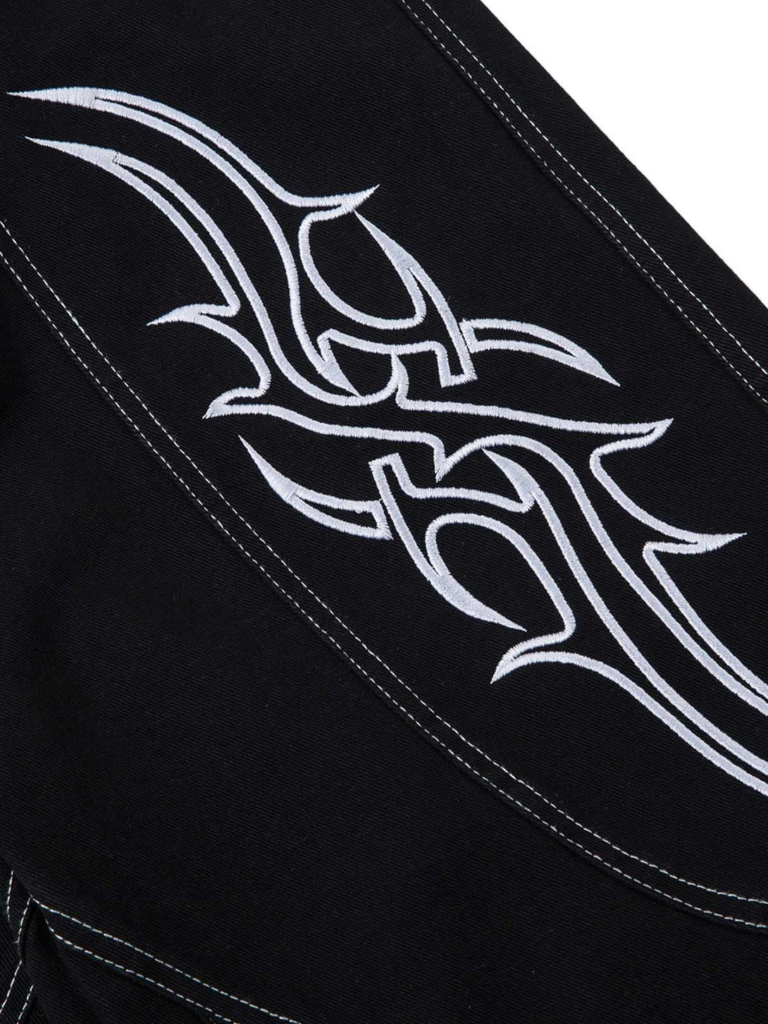 Detailed fabric and stitching on TALISHKO's baggy jeans, highlighting bold embroidery design.