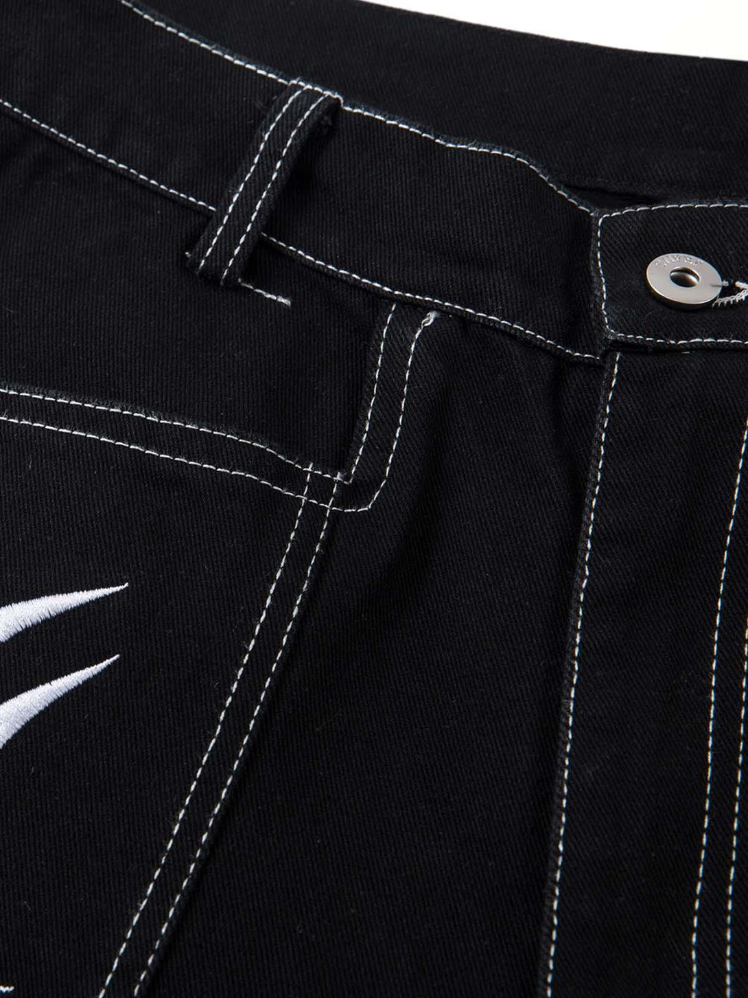 Close-up of TALISHKO's deconstructed baggy jeans highlighting intricate embroidery and stitching.