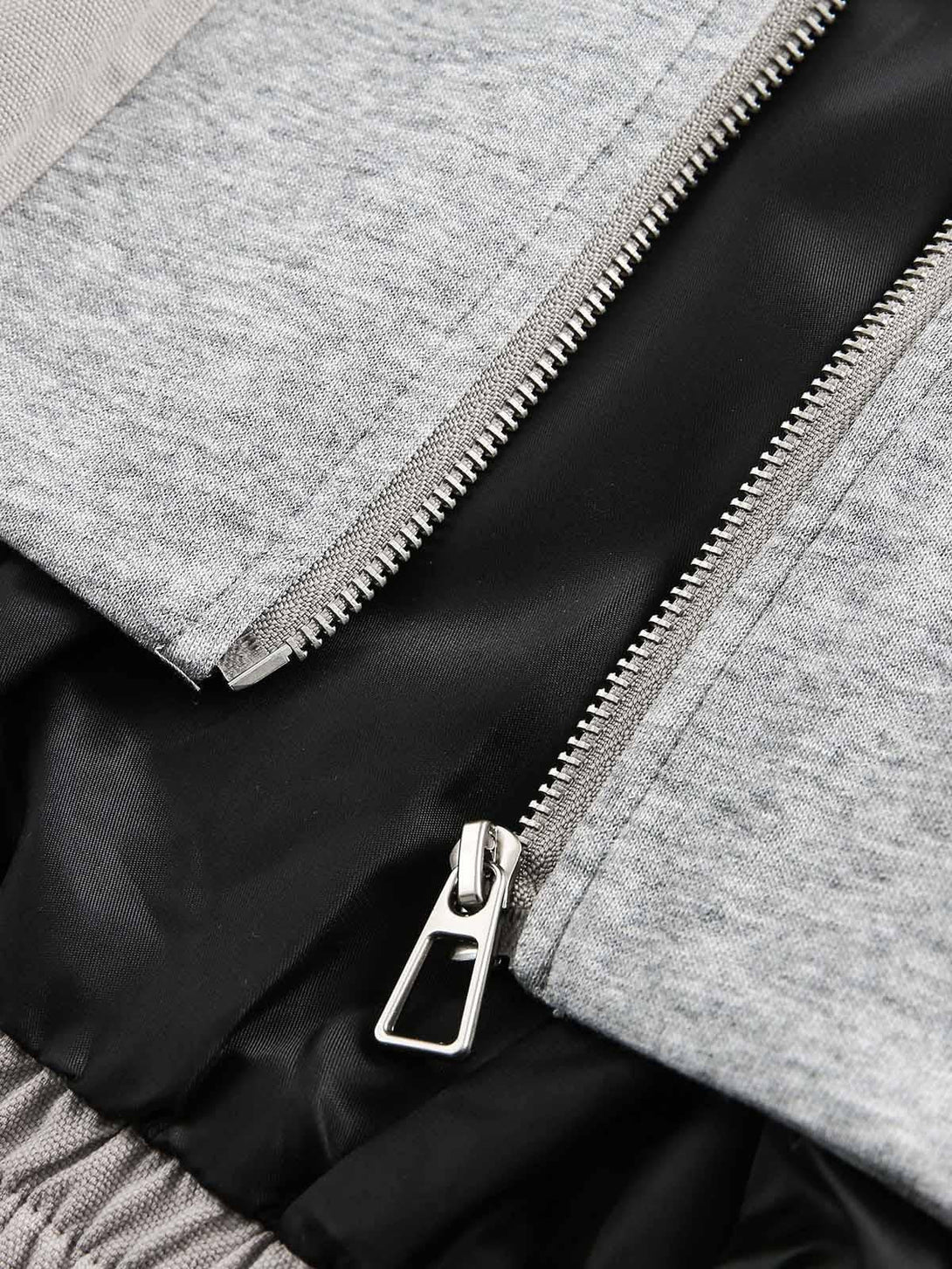 Detailed look at the TALISHKO jacket's gray fabric and zipper, showcasing its deconstructed style.